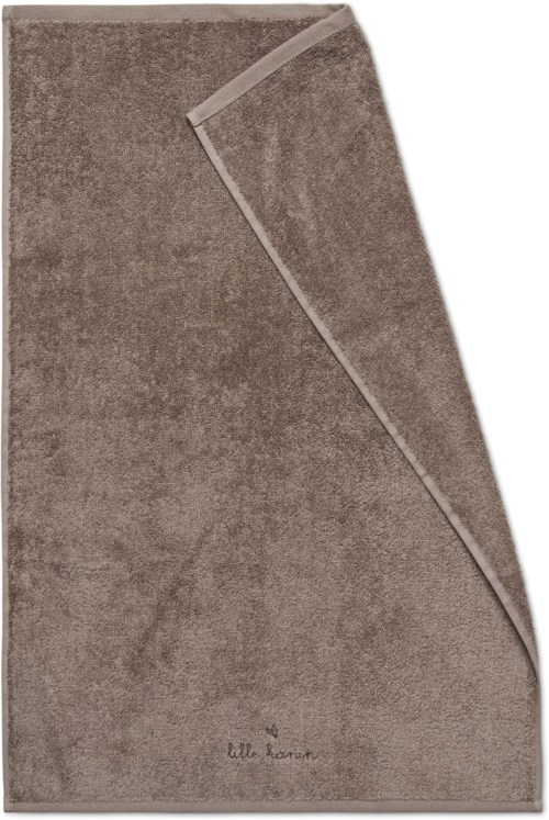 A brown, soft-looking towel with a part folded over itself. The towel has a small logo or text at the bottom.