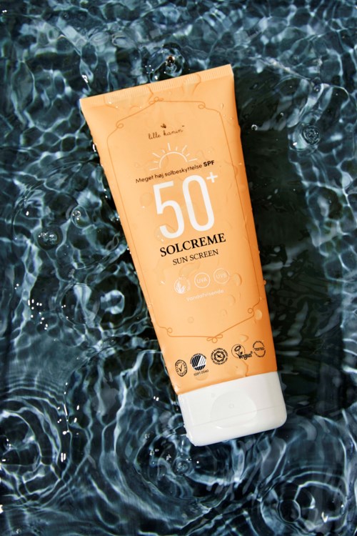 Oranssi aurinkovoiteen.putki, jossa lukee '50+ SOLCREME SUN SCREEN', kelluu vedessä.