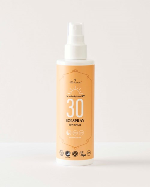 A bottle of sun spray with SPF 30, white pump, orange label, and several certification icons at the bottom.