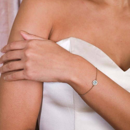 En person i vit klänning visar ett glittrande armband på armen.