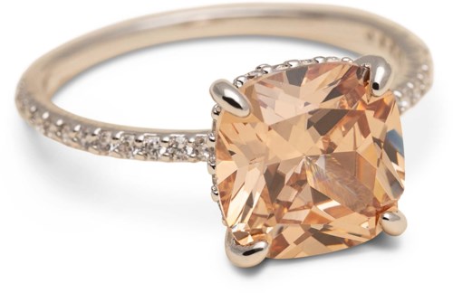 A ring with a large peach-colored gemstone and small clear stones on the band.