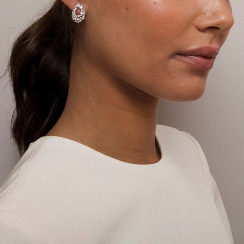 The image shows a woman with long dark hair, wearing a white top and diamond earrings, with focus on her lips and jawline.