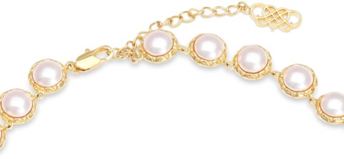 A gold bracelet with round white pearls and a chain extension with a small charm.