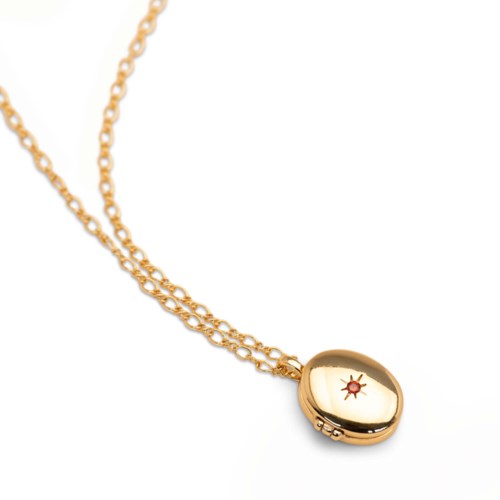 Gold necklace with a round locket featuring a small star-shaped gem or design inside.