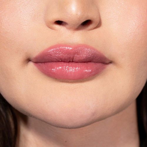 Nahaufnahme von Lippen mit glänzender pinker Lippenstift, glatte Haut und leicht sichtbares Kinn.