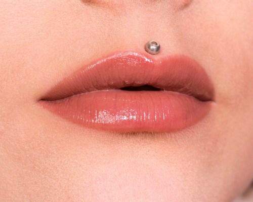 Närbild av läppar med glänsande läppstift och en näspiercing.