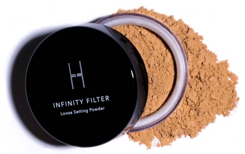 Ein schwarzer runder Behälter mit losen Puder namens 'Infinity Filter' und einem Löffel, mit Pulver verstreut.