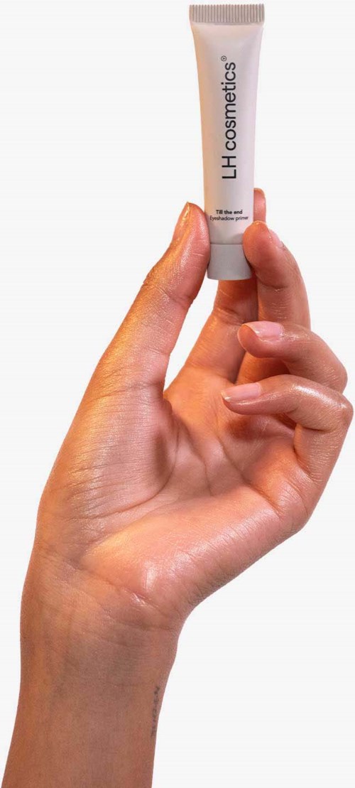 Eine Hand hält eine kleine Tube mit der Aufschrift 'LH cosmetics' vor einem weißen Hintergrund.