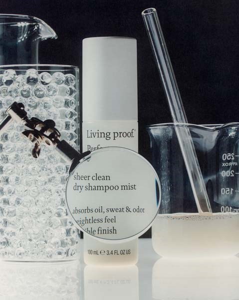 Dry shampoo mist in a white bottle, surrounded by laboratory glassware with bubbles and liquid.