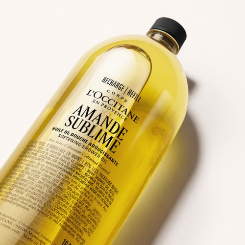 Gelbe Flasche mit L'Occitane Amande Sublime Duschöl mit schwarzem Schraubverschluss und detailliertem Etikett.
