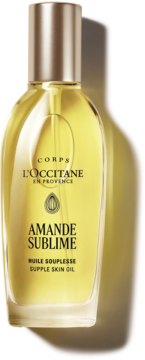 En gul flaska med hudolja och silverlock, märkt L'Occitane Amande Sublime. Den är lätt böjd.