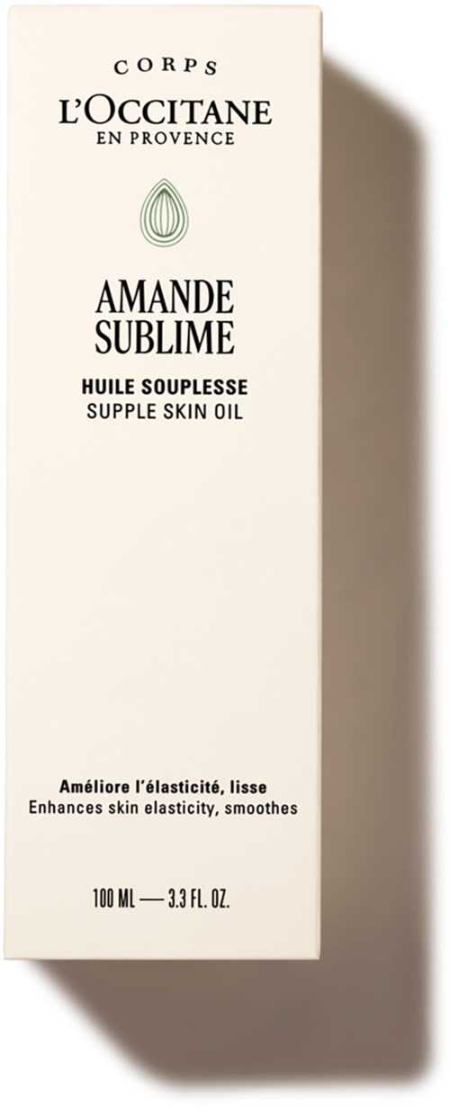En vit låda för L'Occitane hudolja med grön och svart text, står upprätt och kastar skugga.