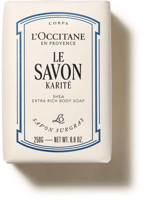 Eine weiße Seife mit blauer Schrift und dekorativen Rahmen, gekennzeichnet als L'Occitane Extra Reicht Körperseife mit Sheabutter.