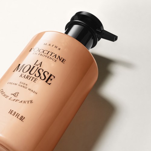 Eine pfirsichfarbene Flasche mit Handwaschmittel von L'Occitane und schwarzem Pumpkopf. Text auf der Flasche enthält Produktname und Details.