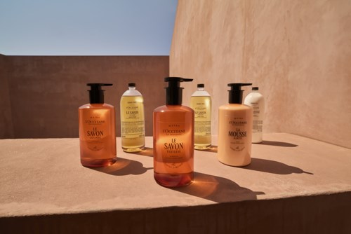Fünf Flaschen Shampoo und Conditioner stehen auf einer Oberfläche im Sonnenlicht, Schatten sichtbar.