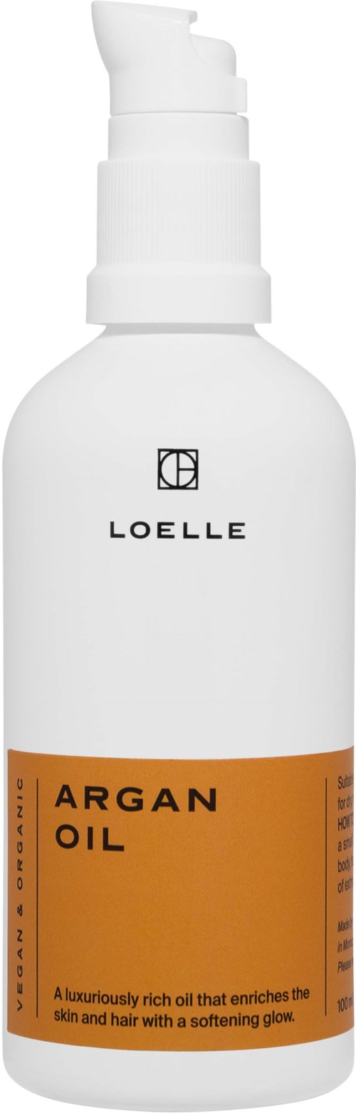 White pump bottle with black text and orange label for argan oil, describes enriching skin and hair with a soft glow.