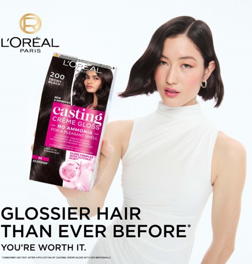Eine Frau mit schwarzen Haaren hält eine L'Oréal Casting Haarfarbe-Box, lächelt, trägt weiße Oberteil, Markenlogo in Ecke.