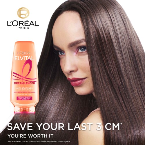 En kvinna med långt, glänsande brunt hår ler mjukt bredvid en flaska L'Oreal Elvital Dream Length-schampo.