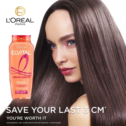 Een vrouw met lang, glanzend bruin haar staat naast een shampoo fles. De shampoo is L'Oréal Elvital Dream Length.