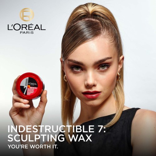 Nainen, jolla on vaaleat hiukset, pitää punaista rasiaa ja mainostaa L'Oréalin Infallible 7 Sculpting Waxia.