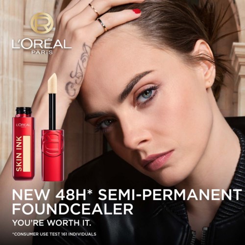Eine Frau mit klarer Haut und Tattoos trägt semi-permanentes Make-up mit einem Pinsel auf, bewirbt L'Oréals neues Produkt.