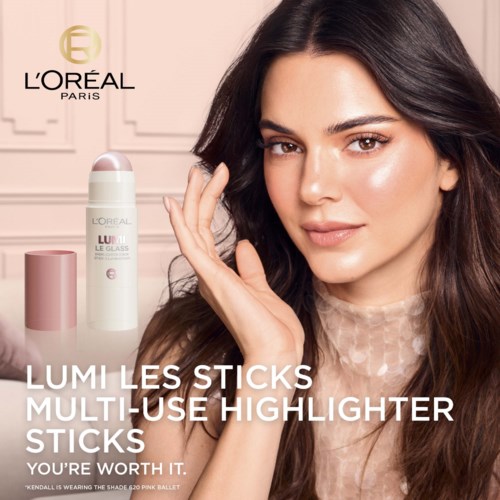 Een vrouw met bruin haar die glimlacht, houdt een highlighter-stift, met L'Oréal Paris-logo en huidverzorgingsproducten op de achtergrond.