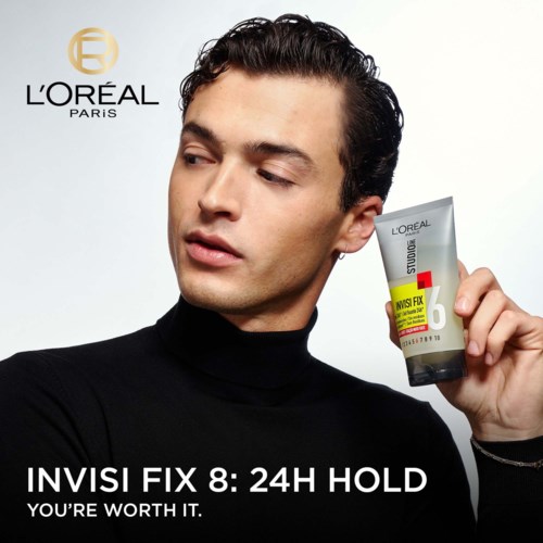 Mężczyzna w czerni trzyma tubkę produktu L'Oréal, z logo i tekstem w tle, promujący stylizację włosów.