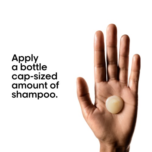 Hand die een ronde shampoo-dop vasthoudt met instructies voor gebruik van een kapselgrote hoeveelheid shampoo.