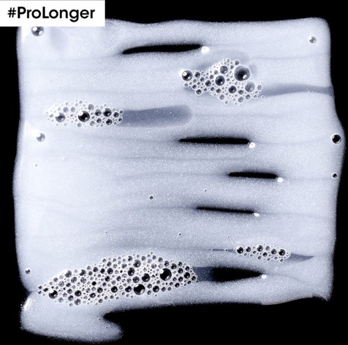 Schuimige bellen drijven op een vloeistof met donkere strepen, gemerkt #ProLonger.
