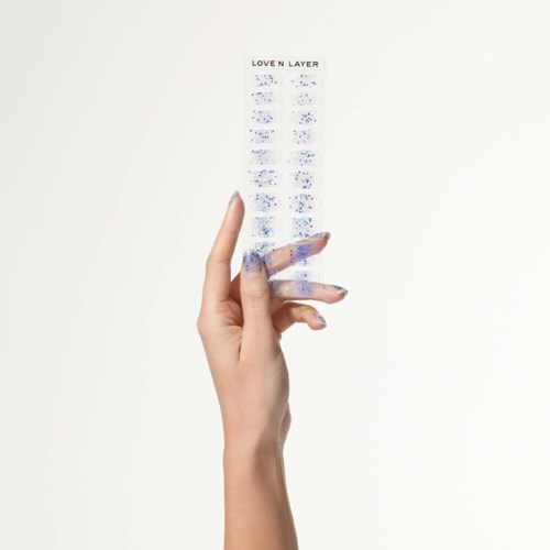 En hand håller en liten, klar plastpåse med blå text som säger "LOVE N LAYER".