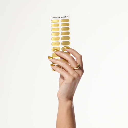 A hand with gold rings holds a palette of yellow makeup shades labeled "LOVE'N LAYER."