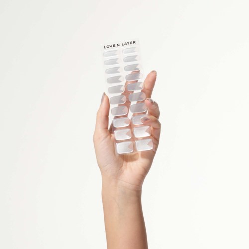 En hand håller en genomskinlig nagellackspalett med olika nyanser, märkt "Loven Layer."