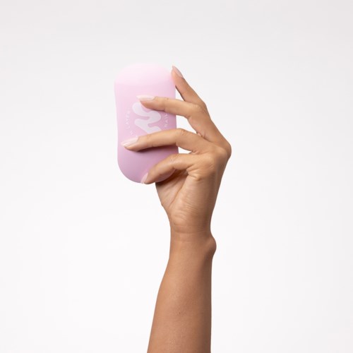 A hand holds a pink makeup sponge with a white logo on a white background.