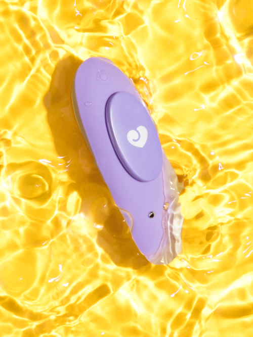 Ein lilafarbenes Handgerät schwimmt im Wasser, umgeben von hellen, sonnigen gelben Wellen und Reflexionen.