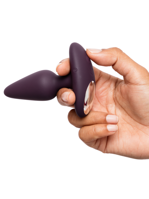 Eine Hand hält ein lilanes, gebogenes und glattes Objekt, möglicherweise ein Handgerät oder Massagegerät.