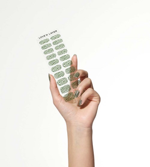 A hand holds a transparent object with multiple green leaves and text that says 'LOVEN LAYER' on top.