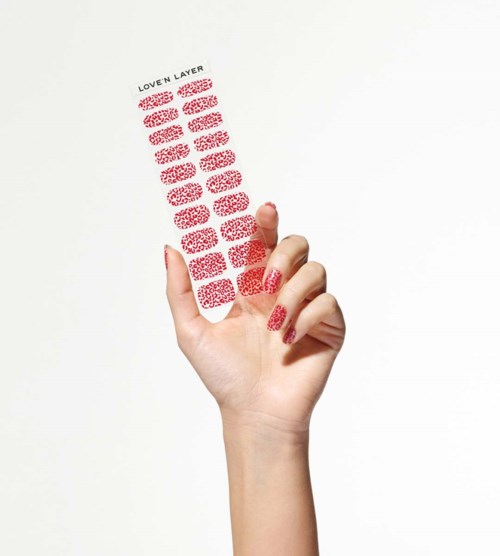 A hand holding a sticker sheet with red patterned layers, labeled "LOVEN LAYERS" at the top.