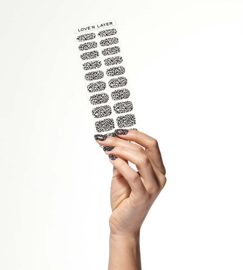 A hand holds a sheet with black and white leopard print sticker nails, labeled "LOVEN LAYER" at the top.