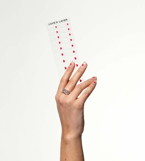 Een hand met ring houdt een blad met rode harten in vier kolommen, gemarkeerd "LOVE N LAYER."