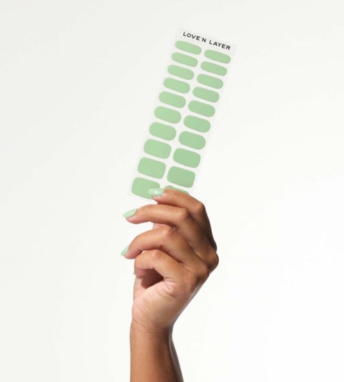 A hand holds a sheet with multiple green oval stickers labeled "LOVEN LAYER."