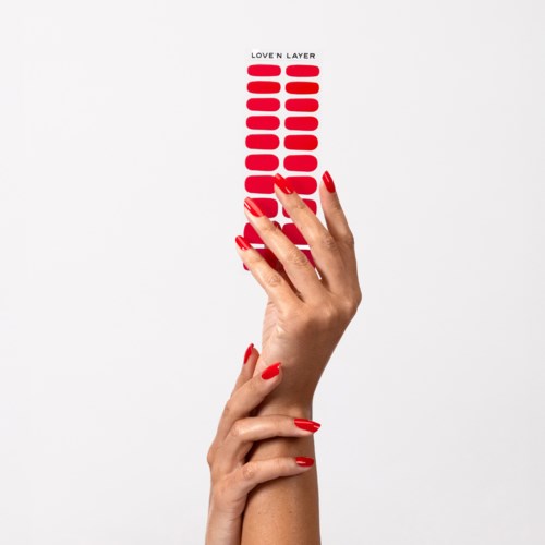 A hand with red nails holds a vertical row of red stickers labeled "Love'n Layer".