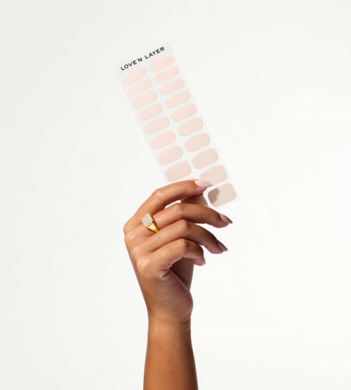 A hand holds a nail polish color sample strip with pink shades, labeled "Loven Layer" at the top.
