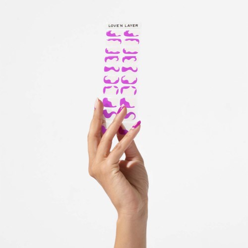 A hand holds a sheet of colorful, decorative stickers with curly shapes and the words "LOVE N LAYER" at the top.