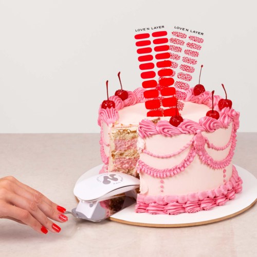 A slice of pink and white layered cake with cherries, decorated with pink icing and labels on a plate.