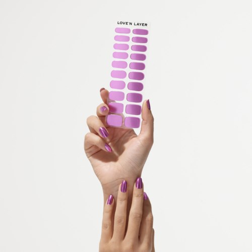 A hand with purple nails holds a purple sticker sheet labeled "Love'n Layer" against a white background.