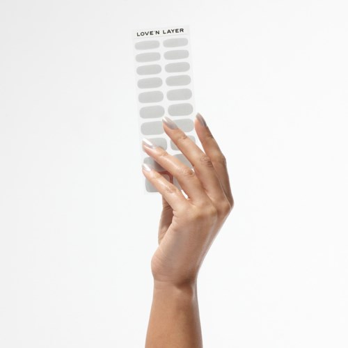 A hand holds a sticker sheet labeled 'LOVE'N LAYER' with empty spaces, floating against a white background.