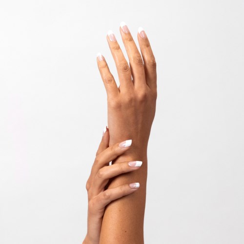 A person's hand with white nails is touching the wrist of the same hand against a plain white background.