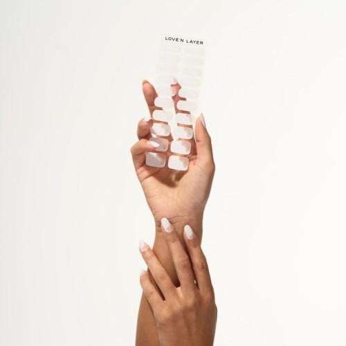 A person holds a plastic nail separator with white nails, featuring the words 'LOVEN LAYER' at the top.