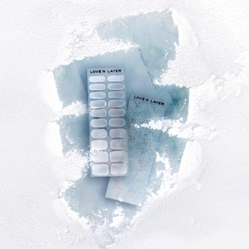 Two blue adhesive strip packages labeled "Loven Layer" on snow with snow spray.