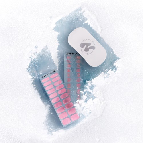 A white container with a black logo, pink nail stickers, and a blue sheet with red numbers.